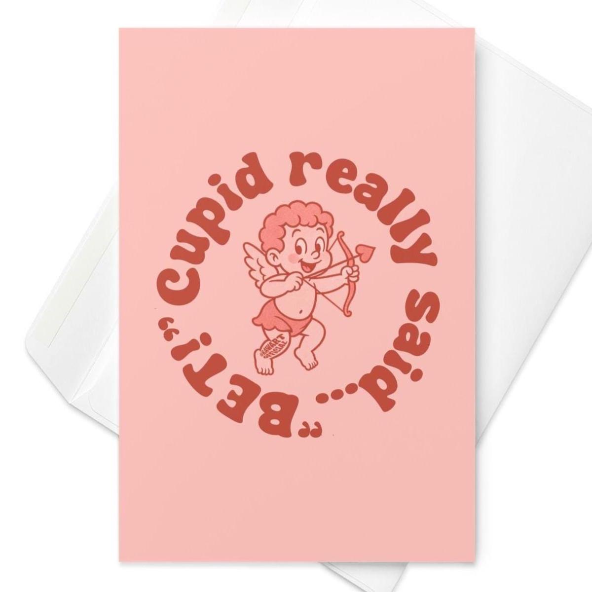 Funny wedding greeting card reading “Cupid Really Said Bet” with retro cupid illustration on a soft pink background.
