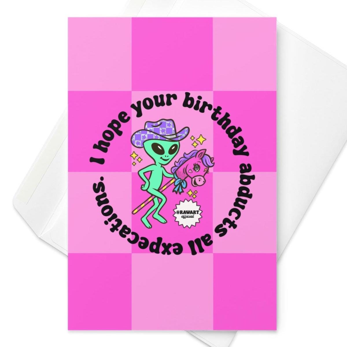 Pink checkerboard birthday card with green alien in cowboy hat riding stick horse under circular text about birthday abduction.