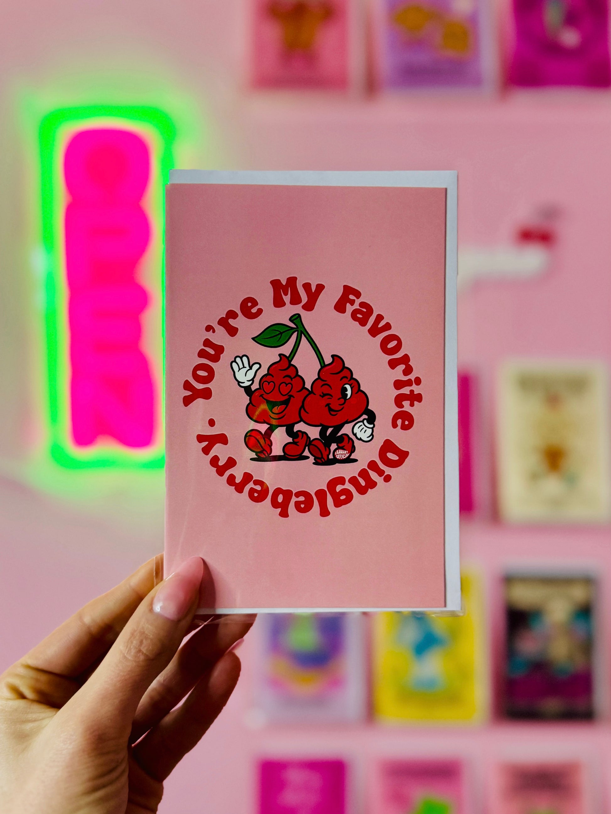 Funny greeting card reading “You’re My Favorite Dingleberry” with two cartoon dingleberries walking together on a pink background.