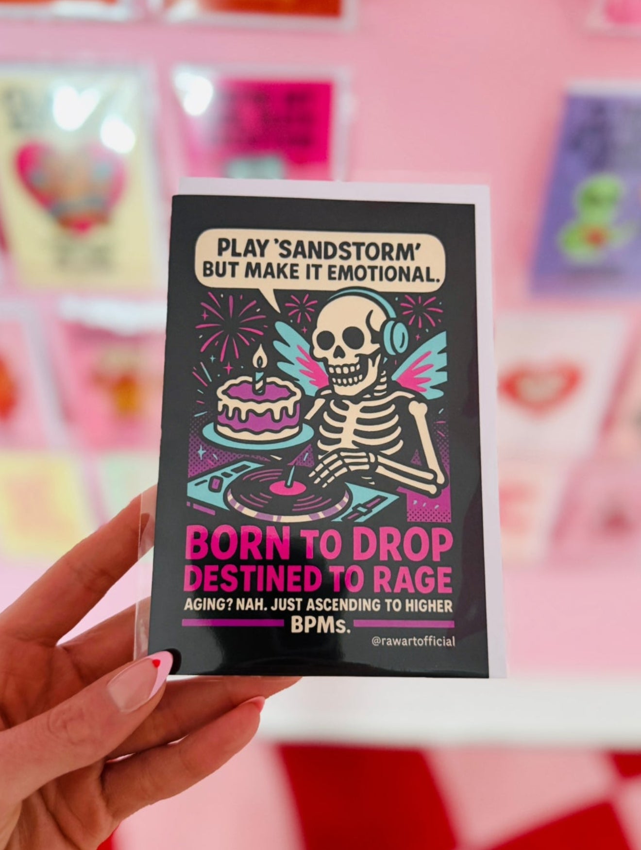 Retro neon comic card with a skeleton DJ spinning records beside a cake with text “Born to Drop, Destined to Rage.”