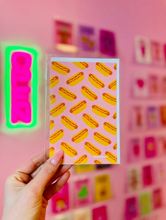 Retro hot dog pattern greeting card with playful pink background and bold orange-yellow hot dogs.