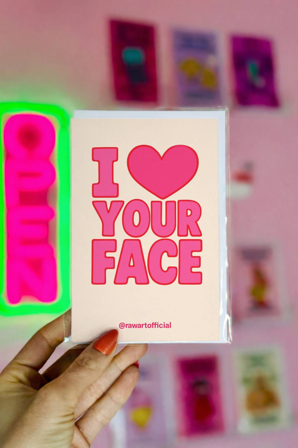 Cream greeting card with bold pink retro text reading I Love Your Face and small @rawartofficial signature at bottom.