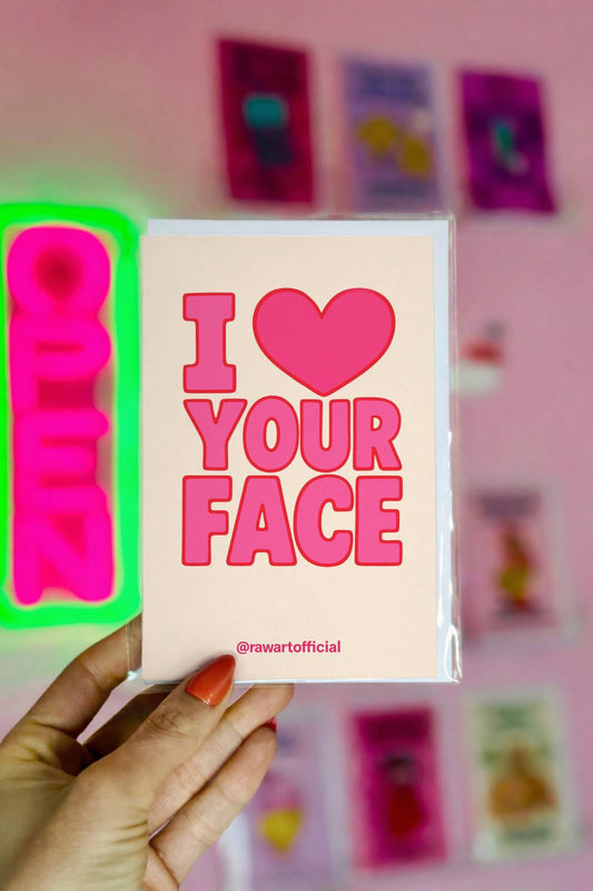 Cream greeting card with bold pink retro text reading I Love Your Face and small @rawartofficial signature at bottom.