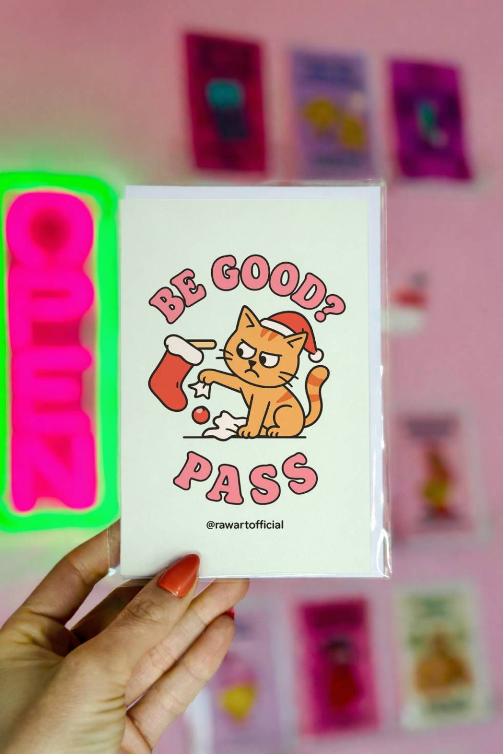 Funny Christmas card with orange cat wearing Santa hat knocking ornaments from a stocking with text “Be Good? Pass.”