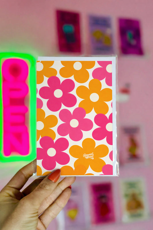 Floral-patterned product with a brand name held by a hand against a pink background with decorative elements.