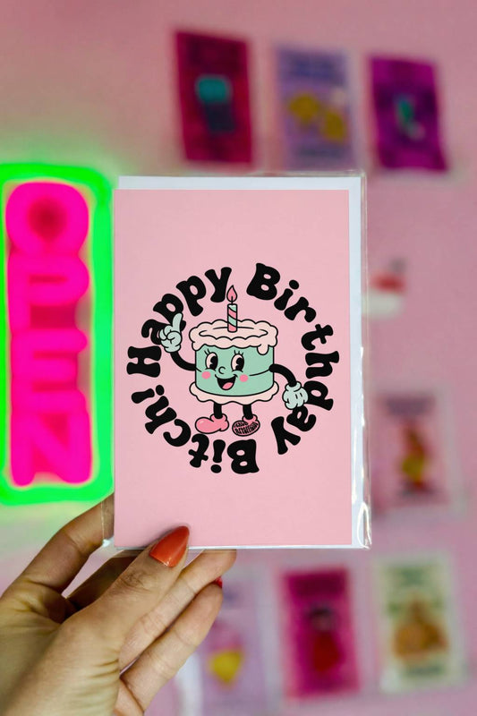 Pink birthday card featuring retro cake with circular text reading “Happy Birthday Bitch.”