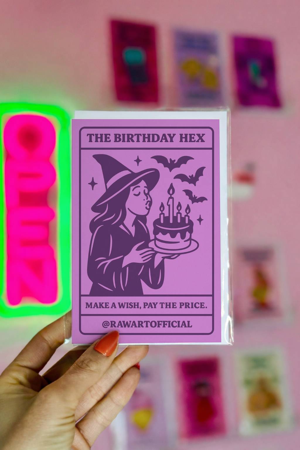 Purple witch birthday card with cartoon witch blowing out candles and bats flying, tarot-style spooky greeting card.