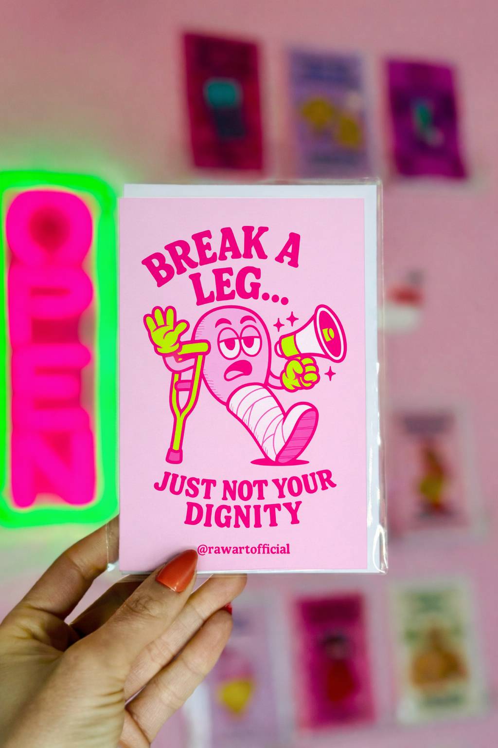 Greeting card featuring a cartoon character with a cast and crutch holding a megaphone with the text “Break a Leg… Just Not Your Dignity.”