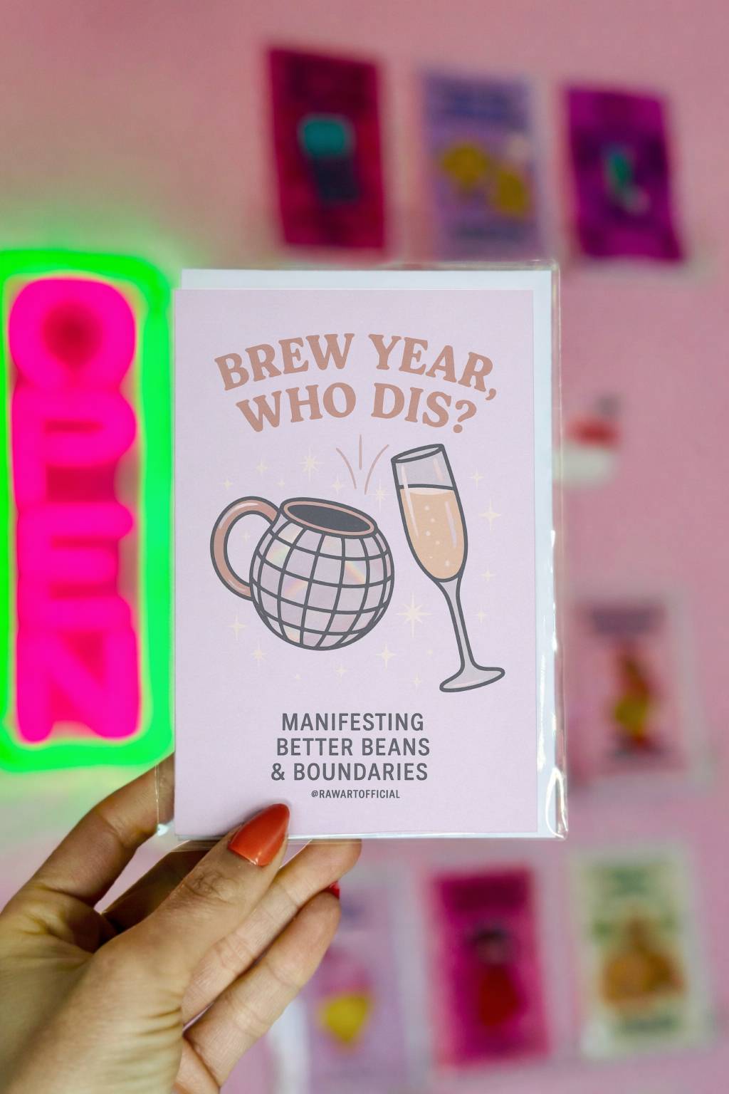 Pastel New Year card featuring a disco ball coffee mug clinking with a champagne glass, surrounded by sparkles, with text reading “Brew Year, Who Dis? Manifesting better beans and boundaries.”