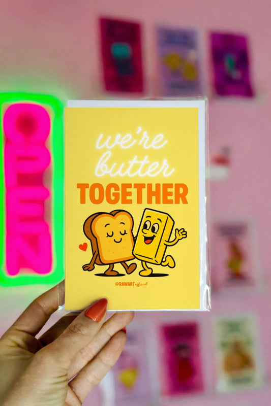 Funny greeting card reading “We’re Butter Together” with a cartoon slice of toast and butter walking together on a yellow background.