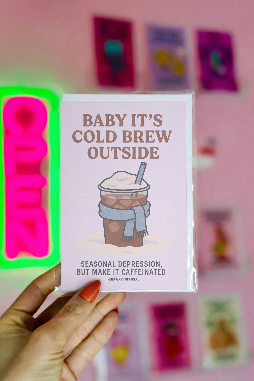 Winter-themed card featuring an iced coffee cup wearing a scarf with the phrase “Baby It’s Cold Brew Outside” and seasonal humor text.