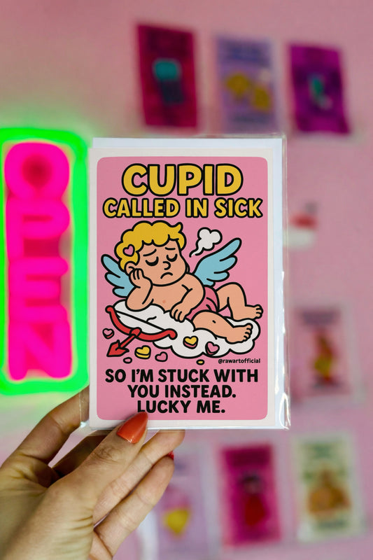 Cartoon Valentine card with a sick cupid lying on a cloud, surrounded by candy hearts, with the text “Cupid Called in Sick.”