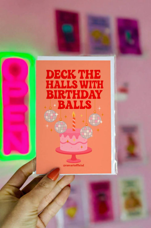 Funny Christmas birthday greeting card featuring a cake with disco ball ornaments and the phrase “Deck the Halls with Birthday Balls.”