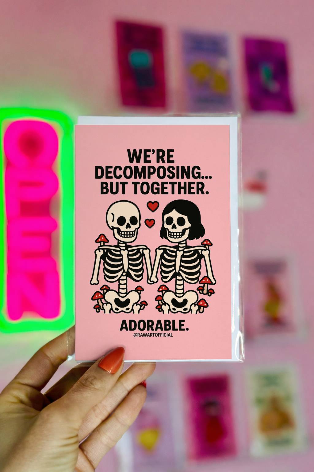 Cute skeleton couple with red hearts and mushrooms, holding hands on a pink background.