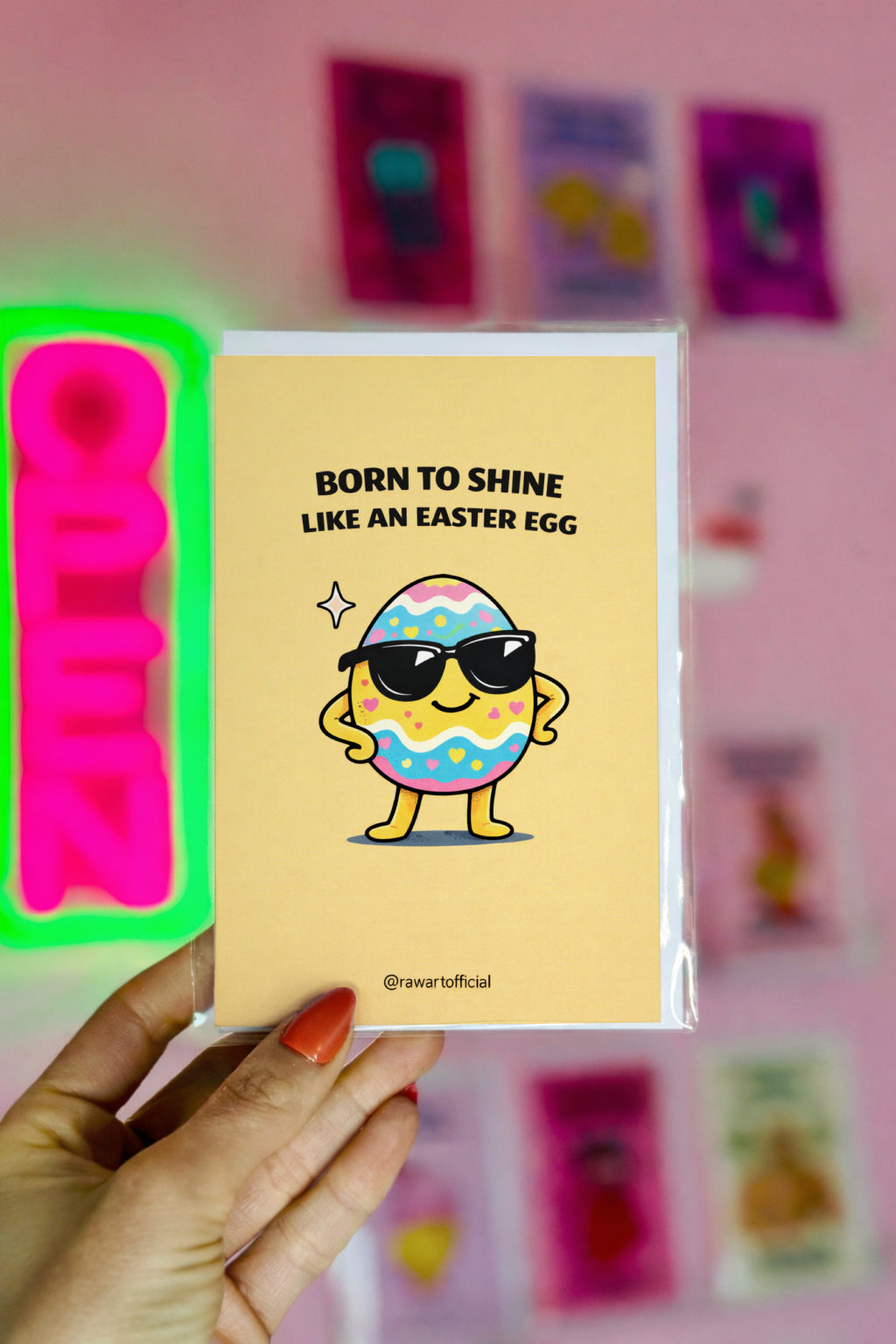 Card with cartoon Easter egg wearing sunglasses and text 'Born to shine like an Easter egg' held by a hand.