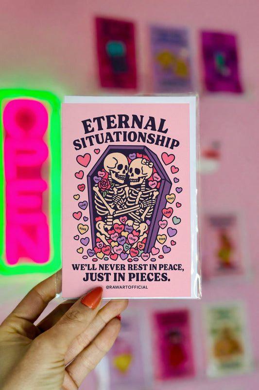 Eternal Situationship greeting card featuring two skeletons cuddling in a pink coffin surrounded by pastel candy hearts with gothic love text.