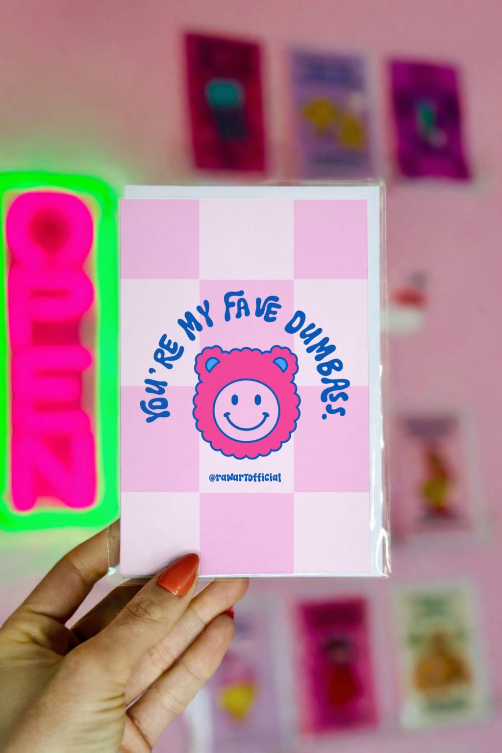 Pink checkerboard card with smiley bear face and text Youre My Fave Dumbass.