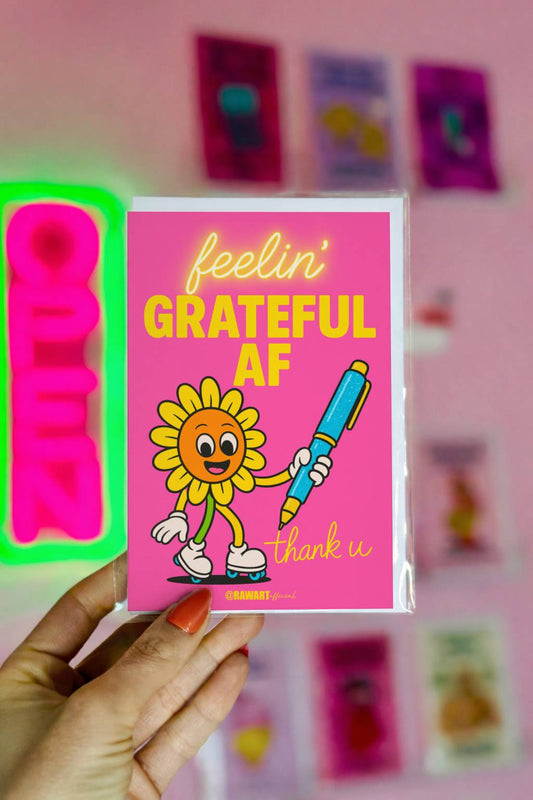 Bright pink thank you card featuring a smiling cartoon flower holding a pen with bold text reading “Feelin’ Grateful AF.”