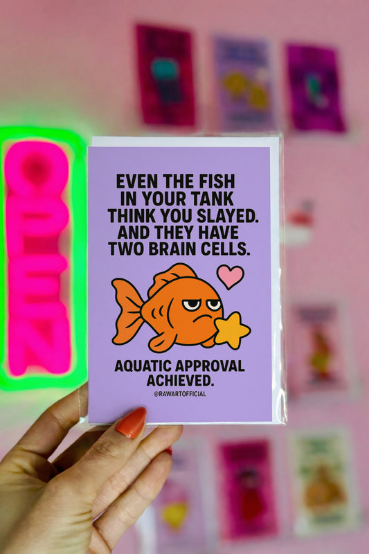 Cute orange goldfish holding a yellow star with text saying “Even the fish in your tank think you slayed… Aquatic approval achieved.” Lilac background.