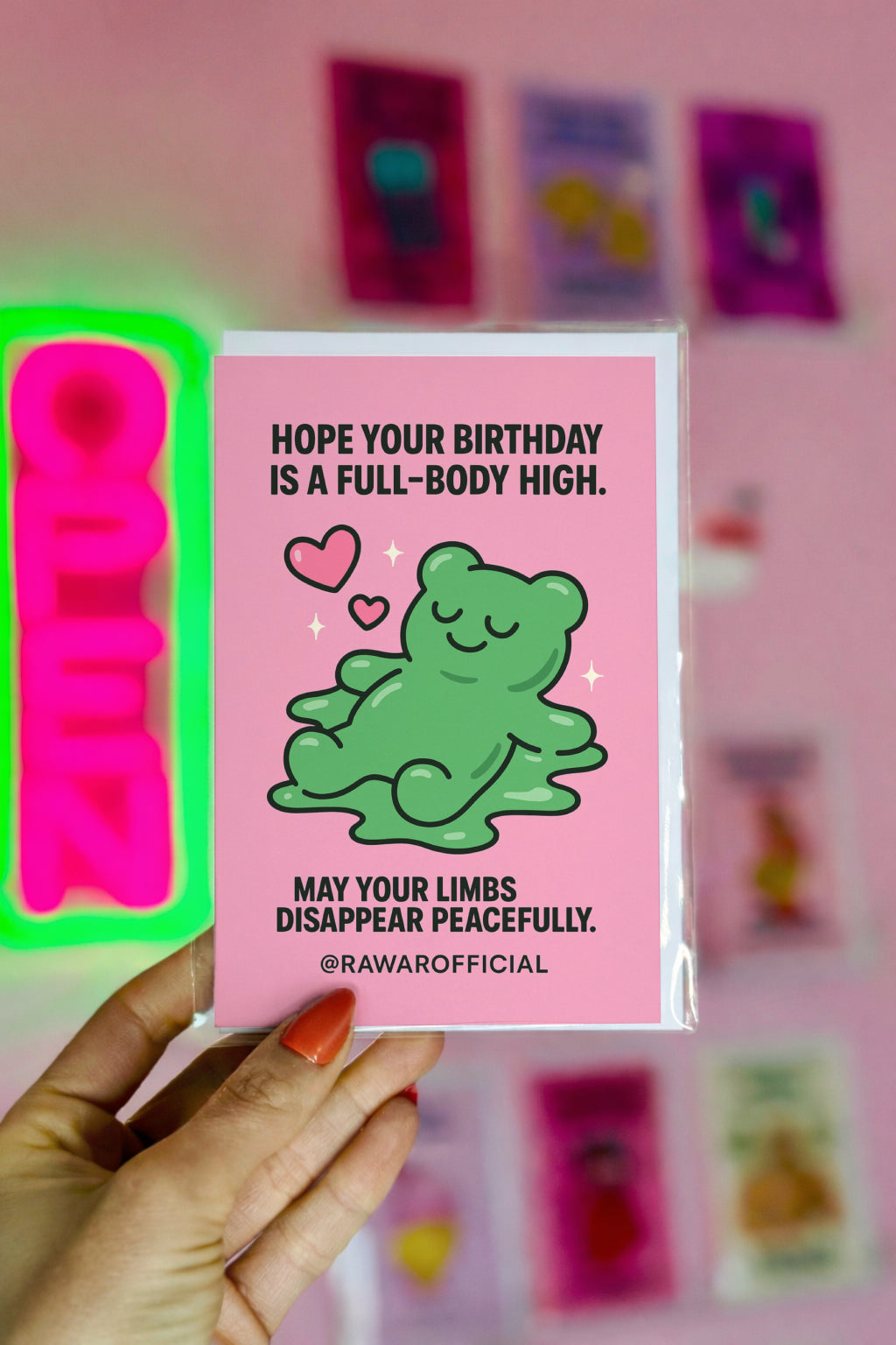 Green melty gummy bear smiling with hearts on pink background, funny stoner birthday card.