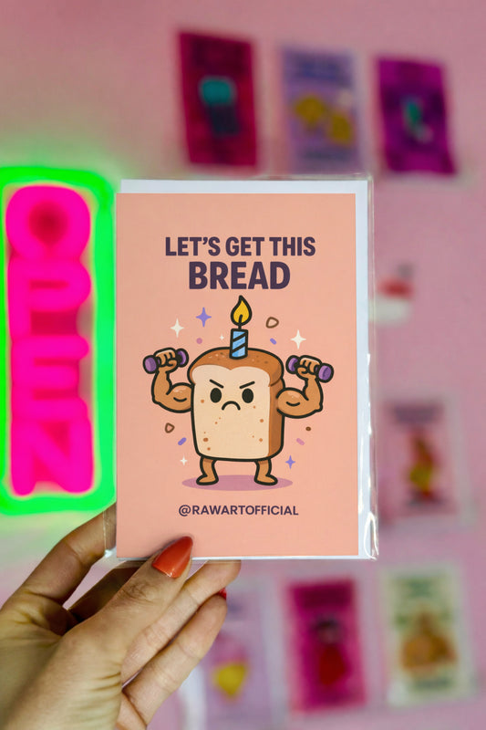 Card with cartoon bread character lifting weights and a birthday candle, held by a hand against a pink background with colorful cards.