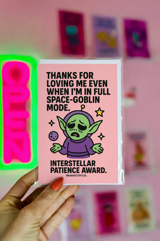 Pink card with sad green space goblin shrugging in a purple suit, with stars and text saying “Thanks for loving me even when I'm in full space-goblin mode.”