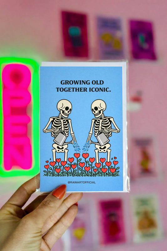 funny anniversary card with two skeletons watering heart flowers on blue background growing old together iconic illustration