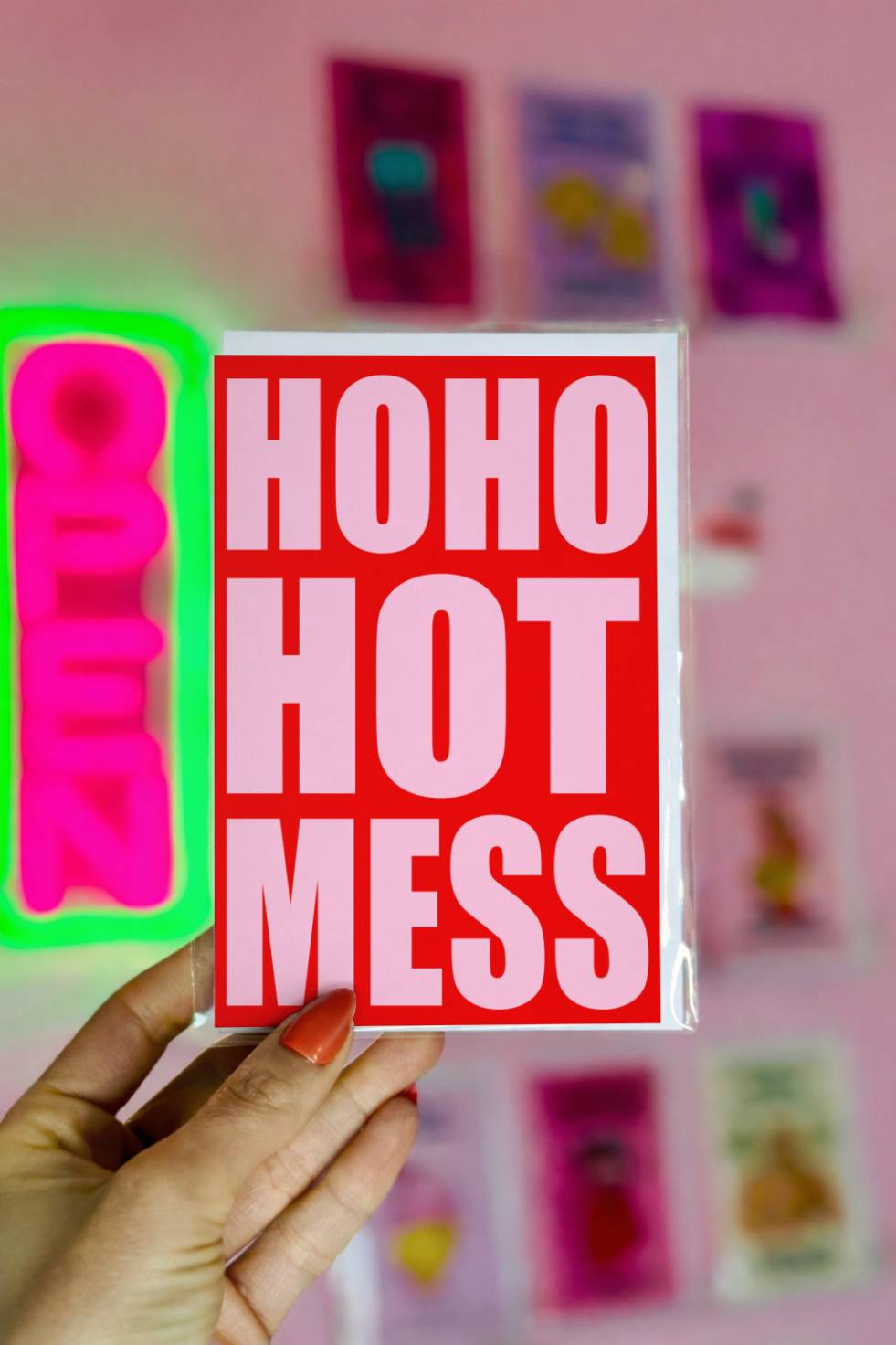 Funny Christmas greeting card with bold pink typography reading “Ho Ho Hot Mess” on a bright red background.