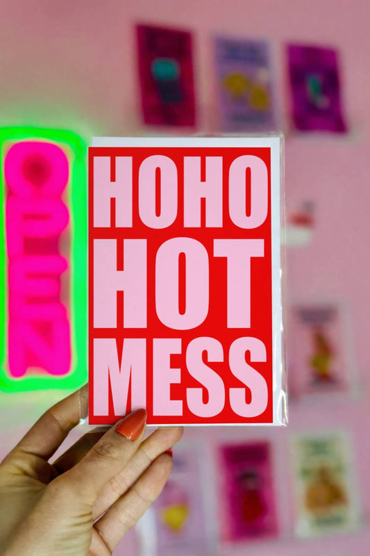 Funny Christmas greeting card with bold pink typography reading “Ho Ho Hot Mess” on a bright red background.