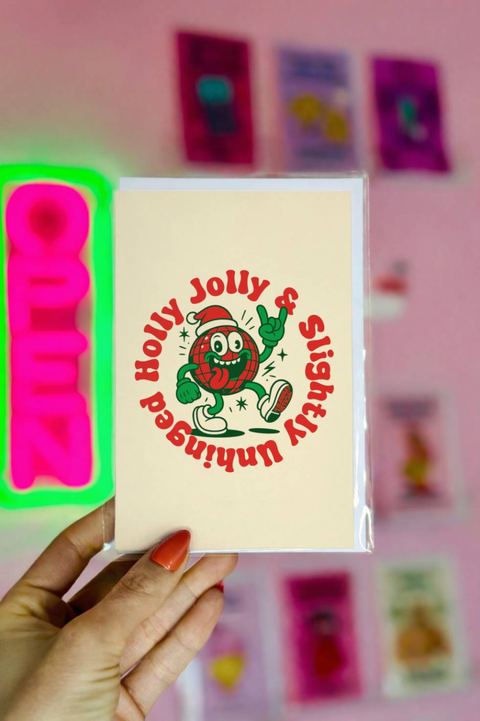 Funny Christmas greeting card featuring a retro disco ball character wearing a Santa hat with circular text reading “Holly Jolly Slightly Unhinged.”