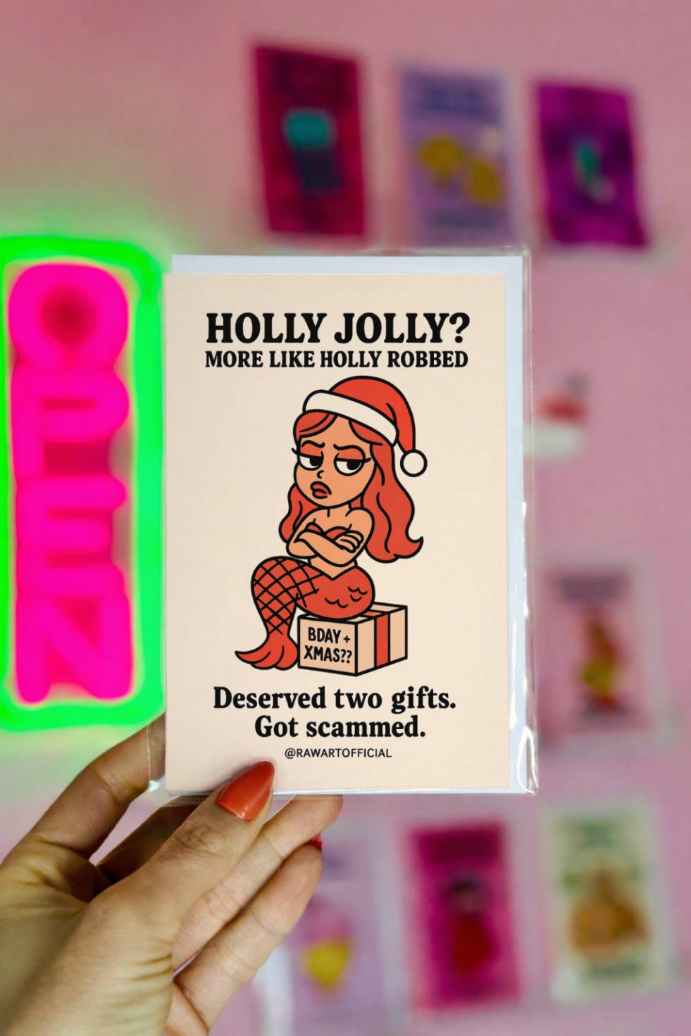 Funny Christmas birthday card with mermaid in Santa hat sitting on present labeled “Bday + Xmas??” with text “Holly Jolly More Like Holly Robbed.”