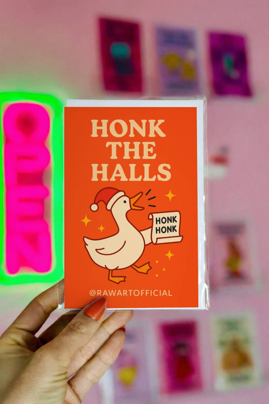 Funny Christmas card showing cartoon goose wearing Santa hat holding a scroll that says “Honk Honk” with text “Honk the Halls.”