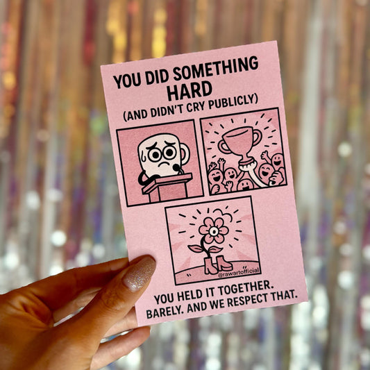 Supportive pastel pink greeting card with black-line comic panels showing a nervous character at a podium, a trophy celebration, and a flower wearing boots. Text reads: “You did something hard (and didn’t cry publicly). You held it together. Barely. And we respect that.”