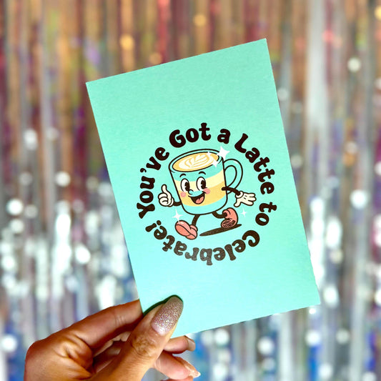 Retro teal greeting card with smiling latte cup and text “You’ve Got a Latte to Celebrate!” in vintage coffee shop style.