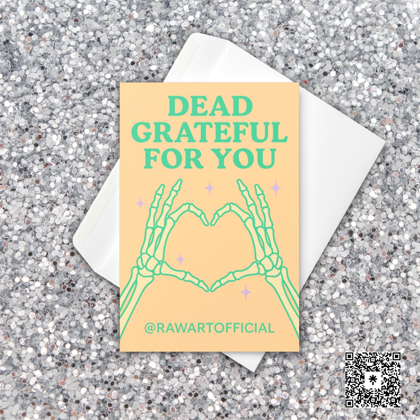Greeting card with skeleton hands forming a heart and the text “Dead Grateful For You” in pastel green on a peach background.