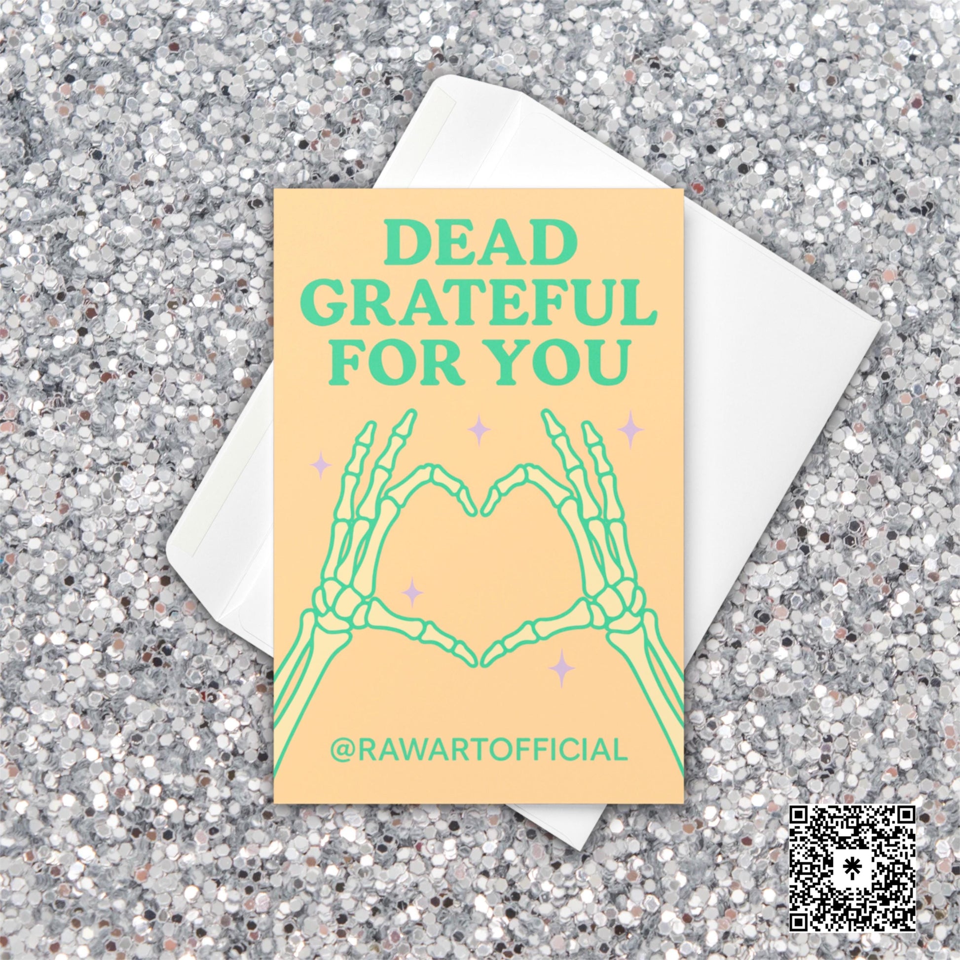 Greeting card with skeleton hands forming a heart and the text “Dead Grateful For You” in pastel green on a peach background.