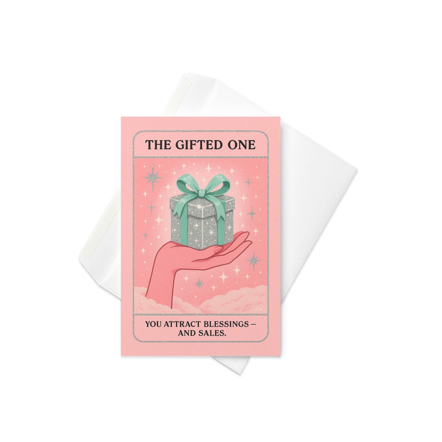 Pastel pink and mint Christmas tarot-style card featuring a sparkling silver gift box with a green bow resting on an illustrated hand, with the text “The Gifted One – You attract blessings and sales.”