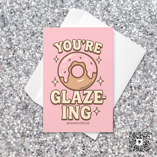 Pink donut with icing surrounded by sparkles and text reading “You’re Glaze-ing,” designed by @rawartofficial.