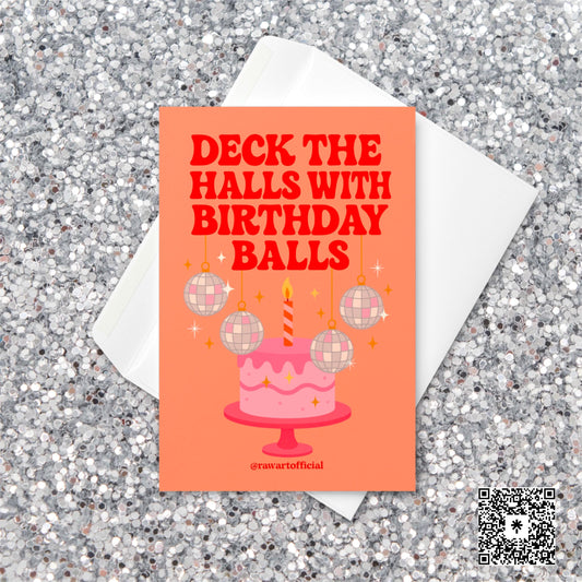 Retro holiday birthday card featuring a pink cake with a striped candle and hanging disco ball ornaments. Text reads “Deck the Halls with Birthday Balls” in bold red letters on an orange background.