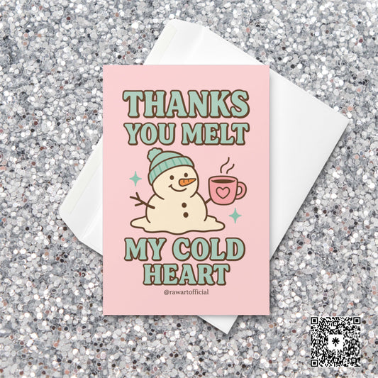 Pink greeting card with melting snowman in a teal hat holding a heart mug, text reads “Thanks You Melt My Cold Heart.”