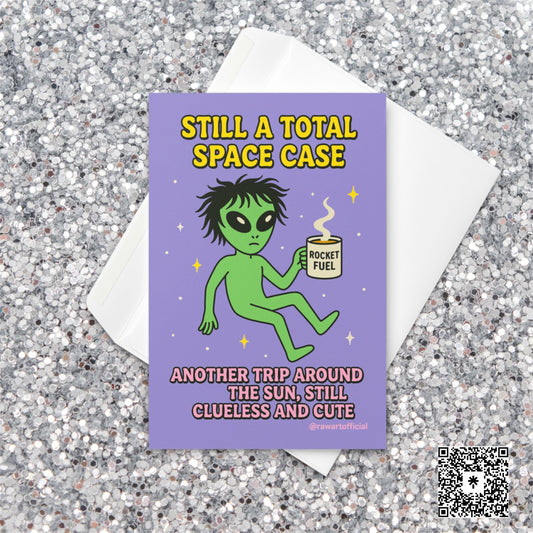 Green alien holding a coffee mug labeled “Rocket Fuel” floating in space with text “Still a Total Space Case.”