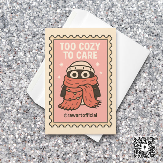 Stamp-style pink holiday card with bundled penguin wearing scarf and beanie, caption reads “Too Cozy To Care.”