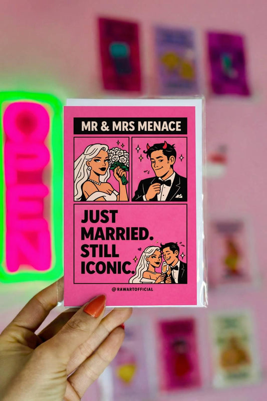 Pink comic-style wedding card featuring a bride and groom with text reading “Just Married. Still Iconic.”
