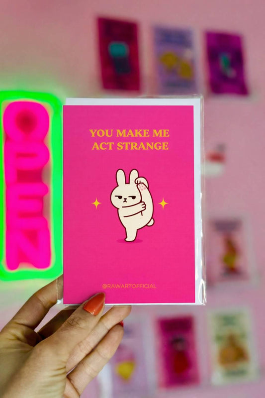 Funny relationship card with text “you make me act strange” on a pink background