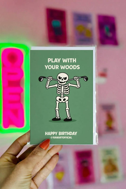 Funny golf birthday design with skeleton holding golf clubs and text “play with your woods” on green background