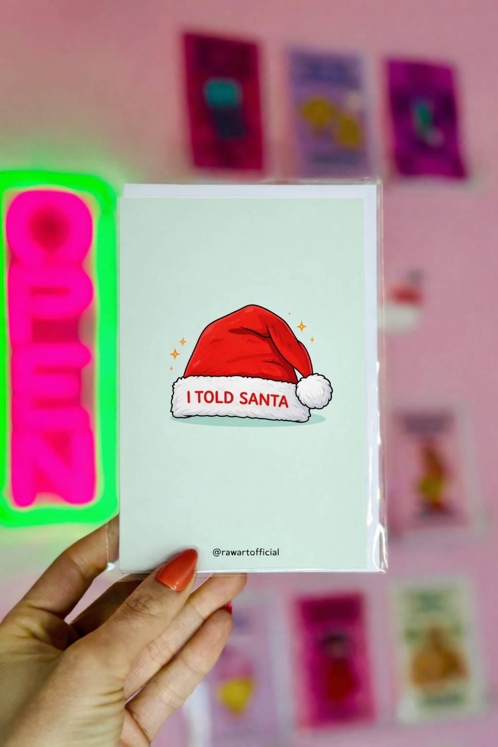 Funny sibling rivalry Christmas card with Santa hat design reading “I told Santa” on light blue background