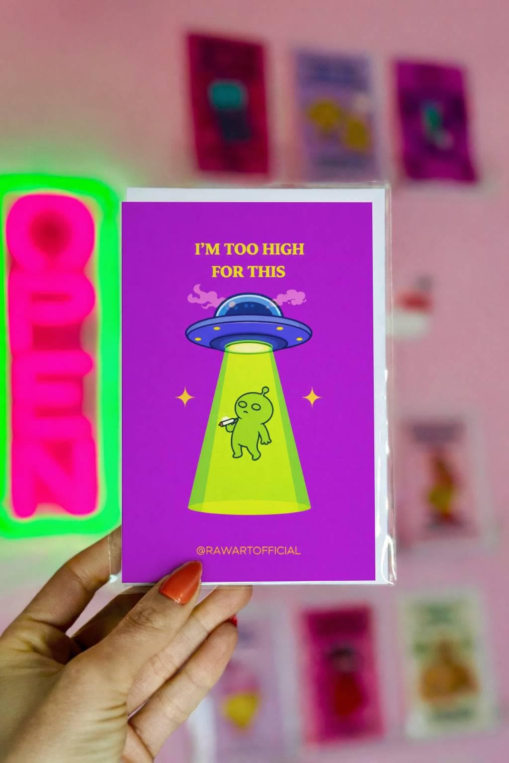 Funny stoner greeting card with alien being abducted by UFO holding joint, text says “I’m too high for this” on purple background