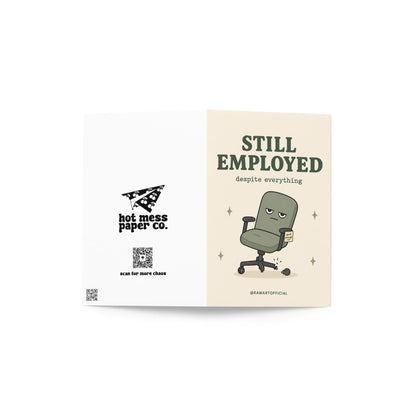 Funny coworker birthday card with broken office chair, text says “still employed despite everything”