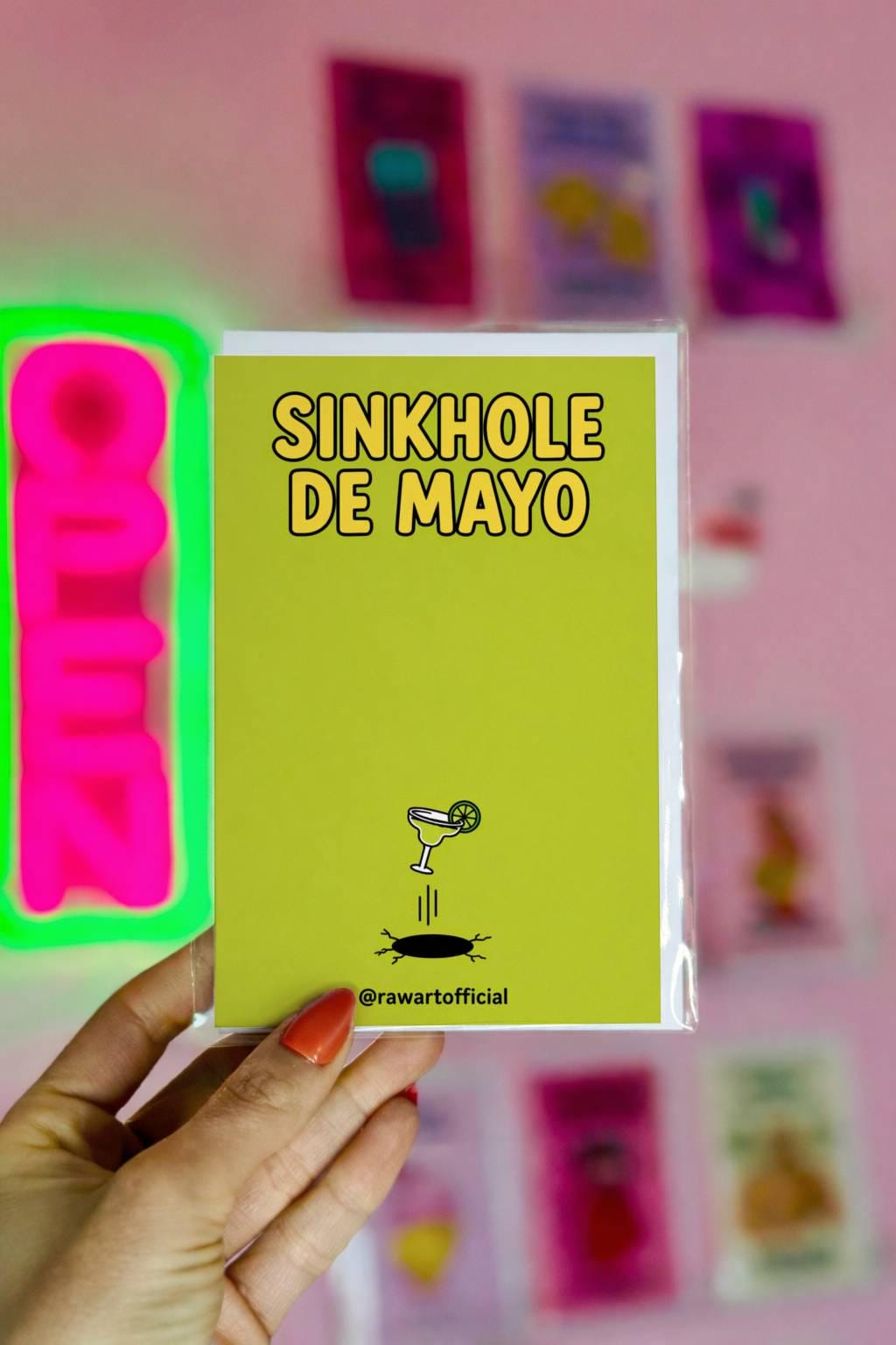 Minimal funny Cinco de Mayo card with a margarita falling into a sinkhole and text “Sinkhole De Mayo” on a green background