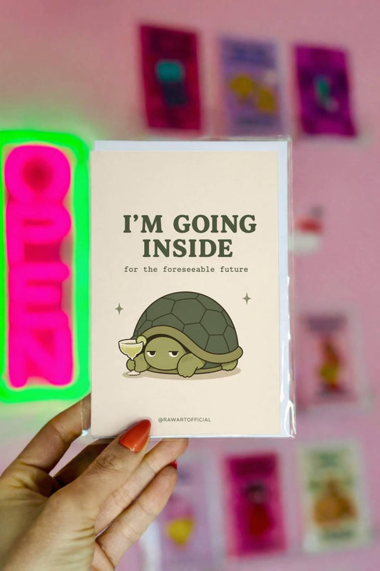Funny introvert greeting card with a turtle holding a margarita and text “I’m going inside for the foreseeable future” on a neutral background